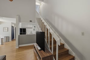 Un interior moderno con una escalera, suelo de madera y una zona de cocina.