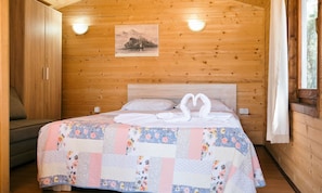 Een houten slaapkamer met een bed, een aan de muur hangend schilderij en een raam.