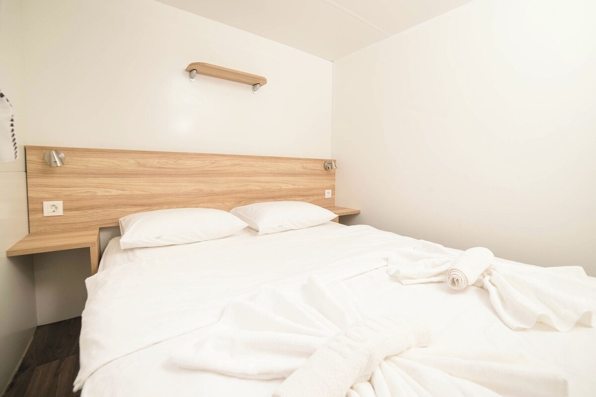 A hotel room with a wooden headboard, a bedside table, and a bed with white linens.