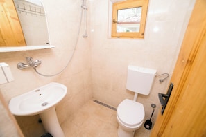 Een badkamer met een wastafel, toilet, douche en een raam.