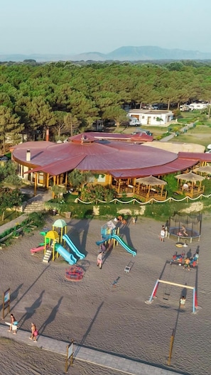 A beachside resort with a large building, a playground, and a sandy area. - Safari Beach & Camping (Ulcinj)