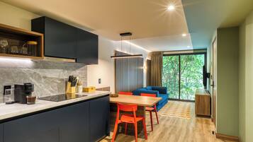 A modern kitchen with dark cabinets, a marble countertop, and a dining area with a wooden table and red chairs.