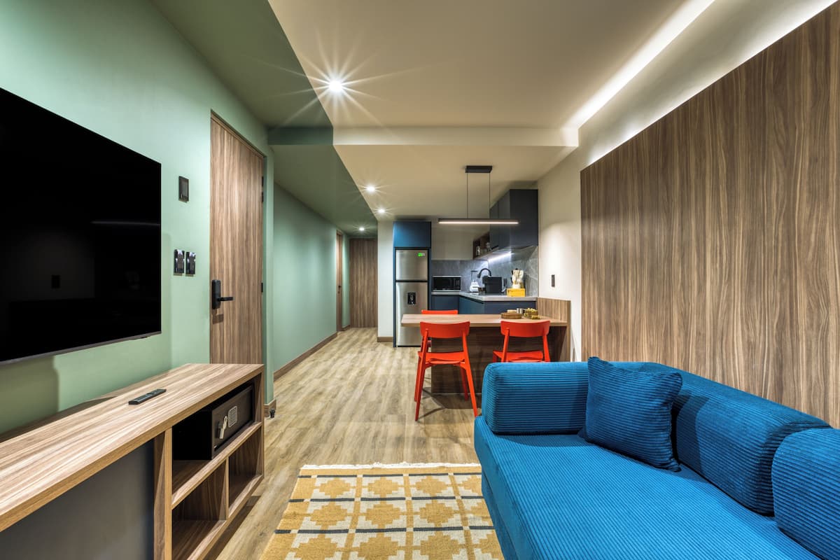 A modern living room with a blue sofa, wooden entertainment unit, and a TV.
