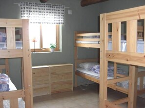 Ein Zimmer mit Etagenbetten, einem Holzschrank und einem Fenster mit Vorhang.