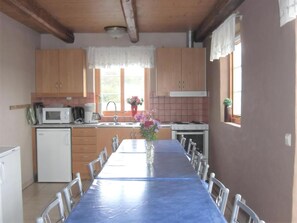 Eine Küche mit Holzausstattung, einer Mikrowelle, einem Spülbecken und einem Esstisch mit Stühlen.