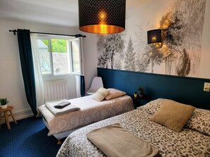 Een slaapkamer met twee bedden, een raam met gordijnen, een wandlamp en een radiator.