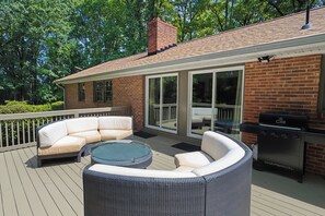 An outdoor patio with a wicker sofa, a glass-top coffee table, and a barbecue grill. - Lakefront 5BR Retreat w/ Private Dock  —Boat Ramp Across Street — Sleeps 14+ (Clarksville)