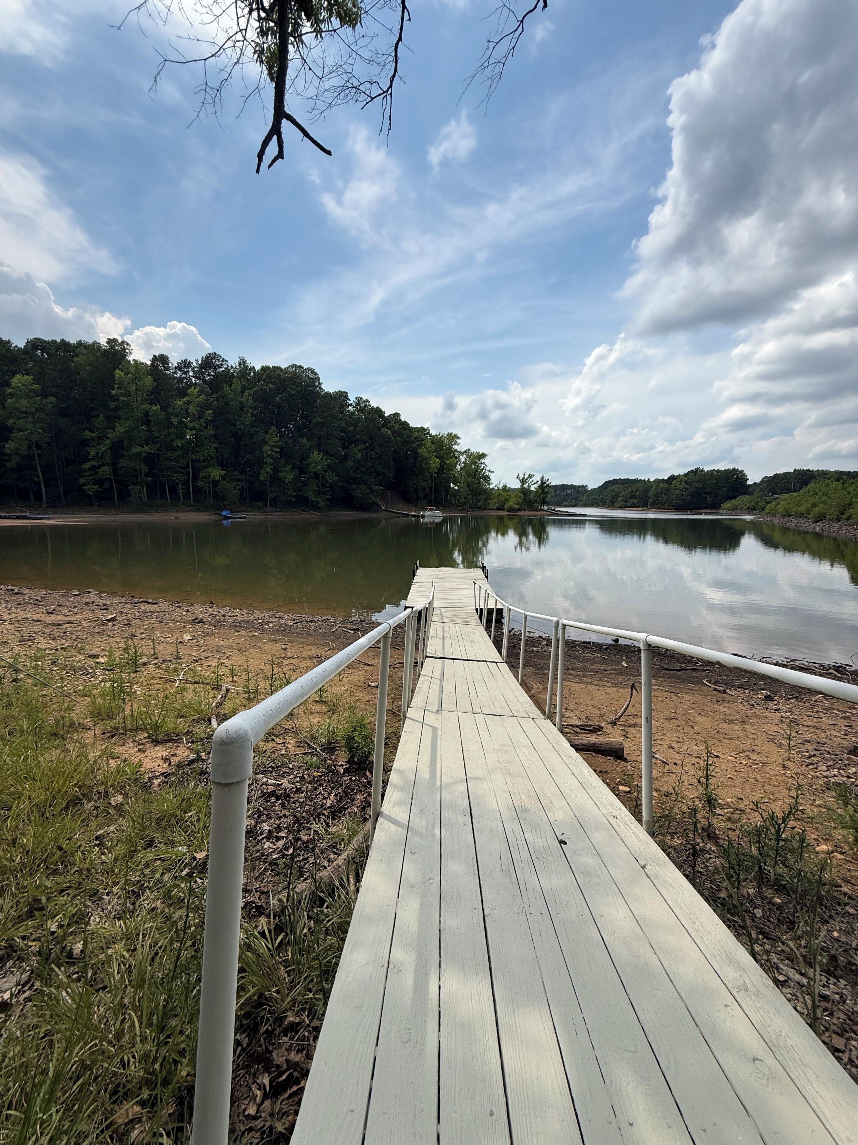A wooden dock leading to a calm lake with a forested shoreline.