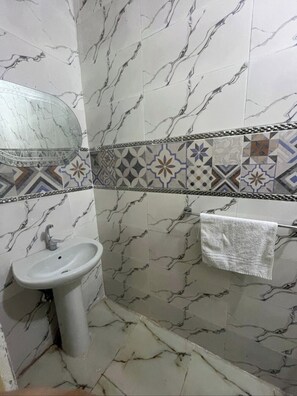 Ein Badezimmer mit Marmorwand, einem Waschbecken, einem Spiegel und einem Handtuchhalter.