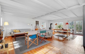 A spacious living area with a high ceiling, a fireplace, a dining table with chairs, and large windows. - Cozy home in Glesborg with house sea view (Glesborg)