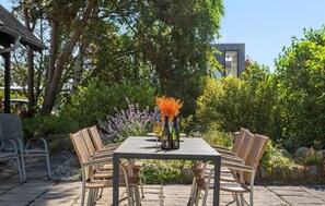 An outdoor patio with a rectangular table, wicker chairs, and a vase with flowers. - Cozy home in Glesborg with house sea view (Glesborg)