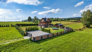 A large house with a swimming pool, surrounded by a fenced garden and a well-maintained lawn. - Luxury Holiday Villa, Pool, Sauna, Jacuzzi (Nowy Targ)