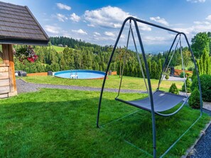 A backyard with a swing set, a swimming pool, and a wooden cabin. - Luxury Holiday Villa, Pool, Sauna, Jacuzzi (Nowy Targ)