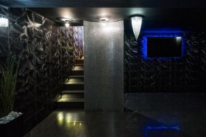 Un interior moderno con una pared texturizada, una escalera, un separador con diseño y un televisor de pantalla plana.