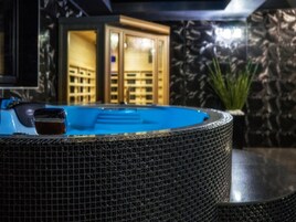 A hot tub with a tiled edge, a wooden cabinet, and a plant in the background.
