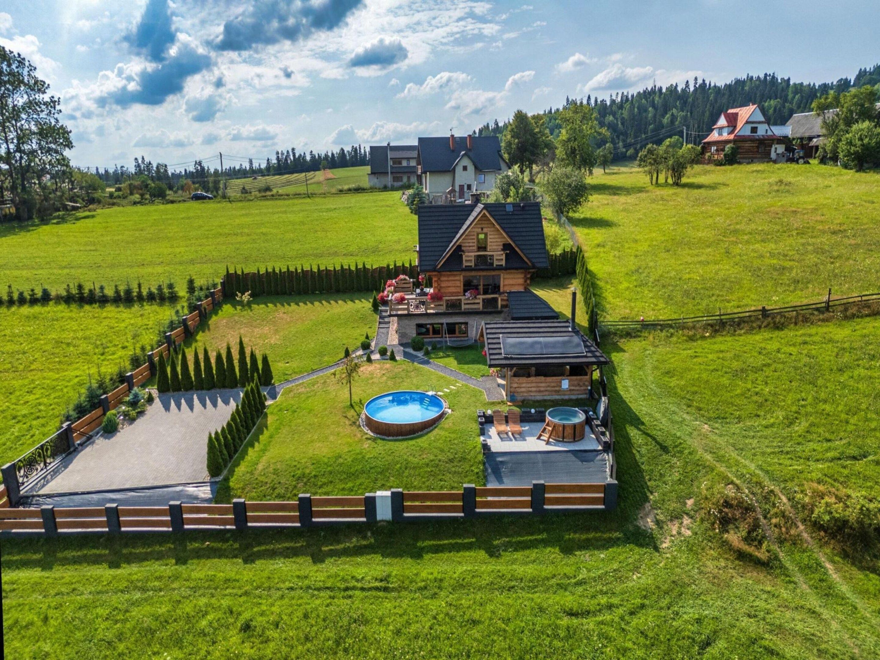 A large house with a swimming pool, hot tub, and a fenced garden area.