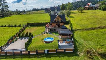 A large house with a swimming pool, hot tub, and a fenced garden area.