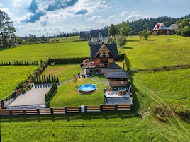 A large house with a swimming pool, hot tub, and a fenced garden area.