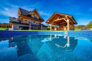 Eine Holzhütte mit Swimmingpool, Steinwänden und blauem Himmel.