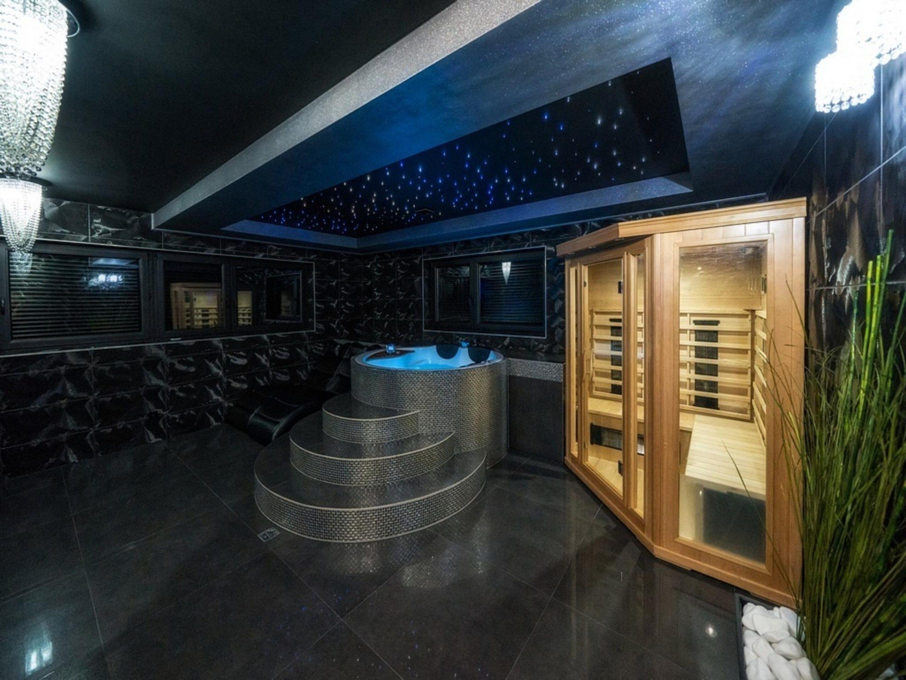 A spa area with a hot tub, a wooden sauna, and a starry ceiling.