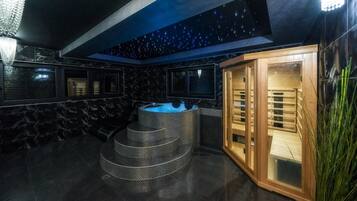A spa area with a hot tub, a wooden sauna, and a starry ceiling.