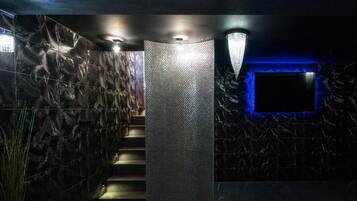 A modern interior with a textured wall, a staircase, and a blue-lit wall feature.