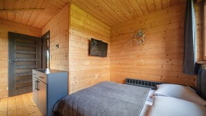 A wooden cabin bedroom with a bed, a small desk, and a television. - Luxury Holiday Villa, Pool, Sauna, Jacuzzi (Nowy Targ)