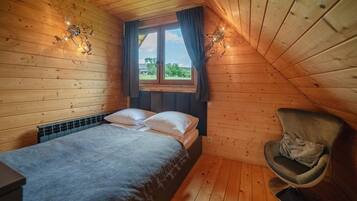 A cozy room with a bed, a chair, and a window with curtains.