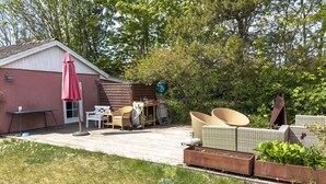 Eine Terrasse mit Gartenmöbeln, einem Geräteschuppen und einem Gartenbereich.