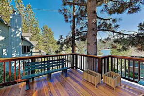 Eine Holzterrasse mit einer Bank und einer kleinen Holzhütte, umgeben von Bäumen.