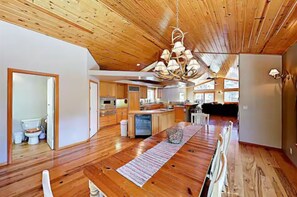 Eine geräumige Küche mit Holzboden, einer Essecke mit Tisch und Stühlen und einer Decke mit Holzbalken.