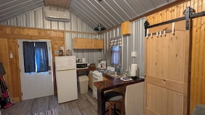 A compact kitchen with a refrigerator, stove, sink, and wooden cabinets. - Cozy 1 room cabin in De Soto! (De Soto)