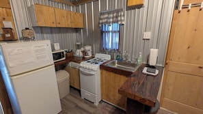 A compact kitchen with a stove, sink, and refrigerator.