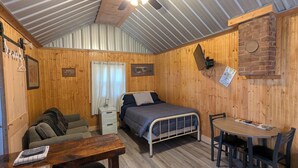 A small, cozy room with a bed, a sofa, a table, and a chair.