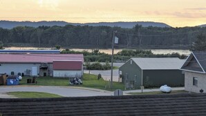 A rural landscape with a building, a road, and a body of water in the background.