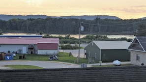 A rural landscape with a building, a road, and a body of water in the background.