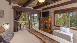 Ein Schlafzimmer mit einem großen Bett, einem Deckenventilator, einem Fernseher, einem Kamin und Blick ins Freie.