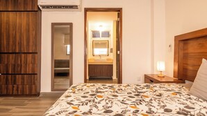 A hotel room with a bed, a nightstand, a lamp, a wooden wardrobe, a mirror, and an air conditioning unit. - Spacious Apartment with Pool and BBQ Area (Mazatlan)