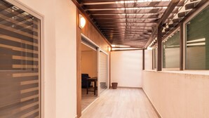 A corridor with wooden flooring, a ceiling with exposed beams, and a door leading to a room with a table and chair. - Spacious Apartment with Pool and BBQ Area (Mazatlan)