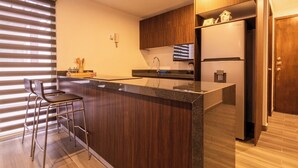 A modern kitchen with a central island, bar stools, a refrigerator, and a built-in oven. - Spacious Apartment with Pool and BBQ Area (Mazatlan)