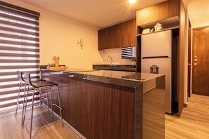 Eine moderne Küche mit einer zentralen Kochinsel, Barhocker, einem Kühlschrank und einem Einbauofen.