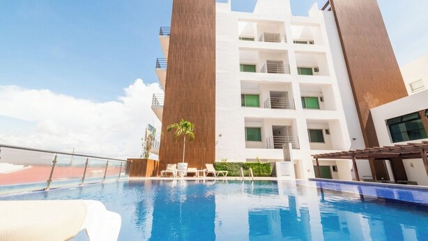 A modern hotel with a swimming pool, multiple balconies, and a clear sky. - Spacious Apartment with Pool and BBQ Area (Mazatlan)