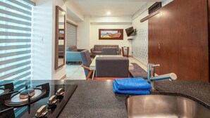A modern kitchen with a gas stove, a sink, and a dining area with a table and chairs. - Apartment for 6 on the first floor with pool (Mazatlan)