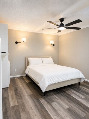 Ein Schlafzimmer mit einem Bett, einem Deckenventilator und zwei Wandleuchten.