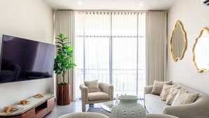 Una sala moderna con un televisor de pantalla plana, un sofá, una silla, una mesita de centro y un jarrón decorativo.