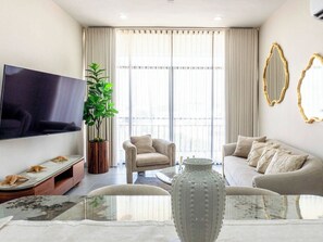Ein modernes Wohnzimmer mit Flachbildfernseher, einer Couch, einem Sessel, einem Couchtisch und einer dekorativen Vase.