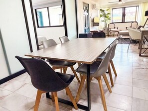 Een vergaderruimte met een lange tafel en stoelen, een televisietoestel en een plant.