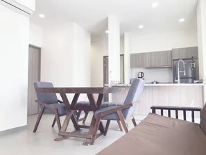 Eine moderne Küche mit grauen Schränken, einem Edelstahlkühlschrank und einer Kaffeemaschine.