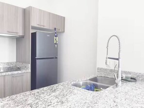 A kitchen with a stainless steel sink, a refrigerator, and granite countertops. - Centrica Suite A con Alberca en Mazatlán (Mazatlán)
