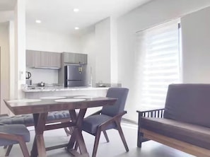 A modern kitchen with a built-in refrigerator, a dining table with chairs, and a sofa. - Centrica Suite A con Alberca en Mazatlán (Mazatlán)